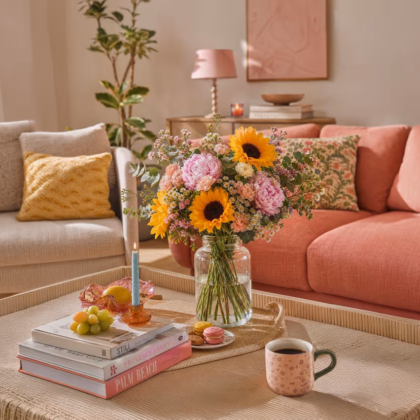 Arrangement mit Sonnenblumen und Pfingstrosen in einem Wohnzimmer